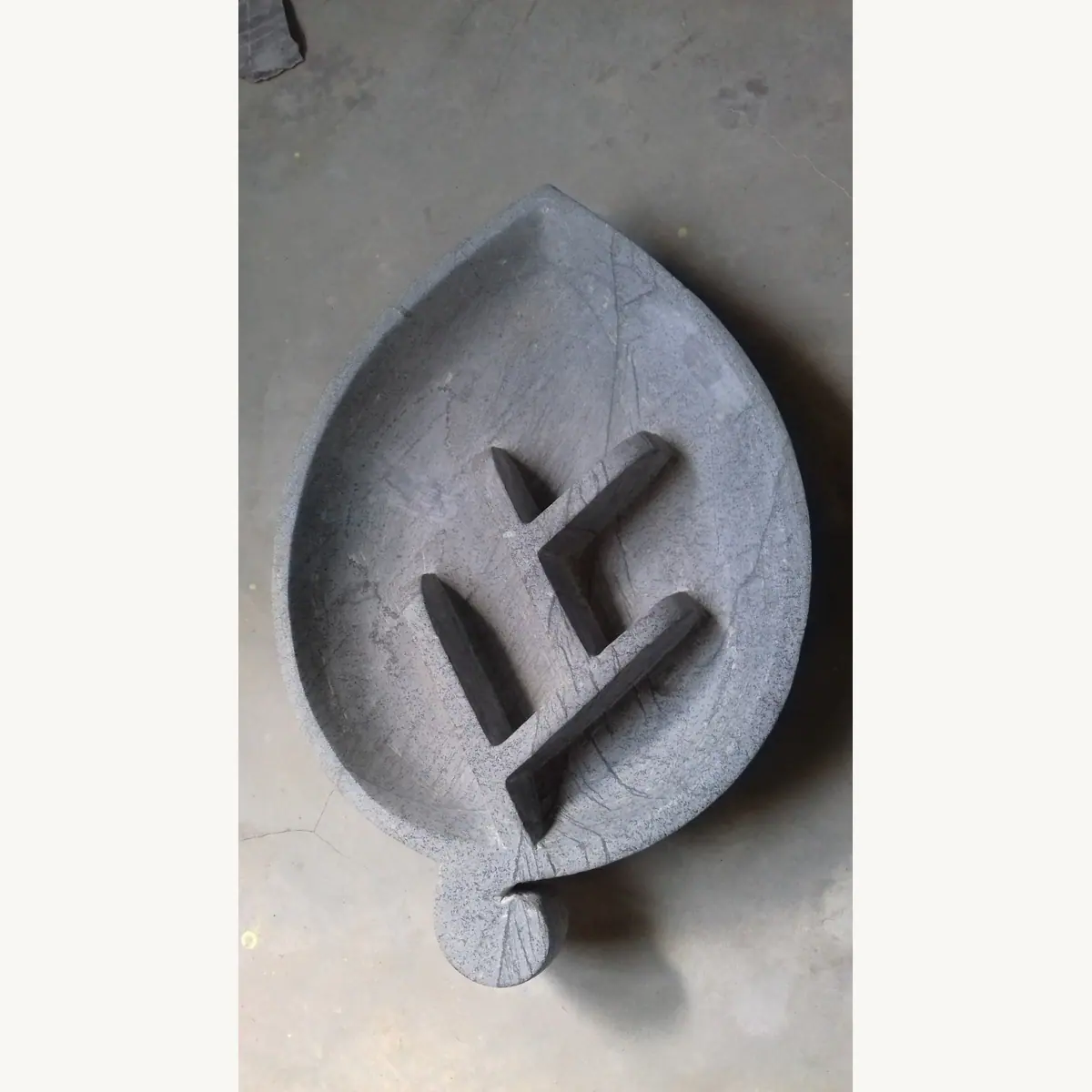 Leaf-shaped decorative stone bowl with a carved symbol