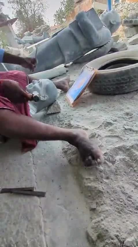 An artisan shaping a stone portrait by hand in a Shivarapatna workshop
